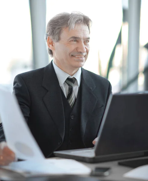 Lächelnder Geschäftsmann sitzt an seinem Schreibtisch — Stockfoto