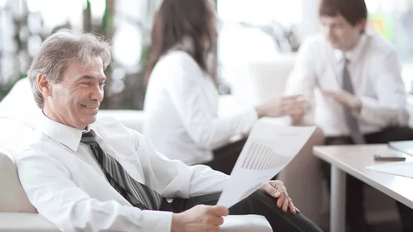 Hombre de negocios ponderando un documento sentado en una oficina moderna — Foto de Stock