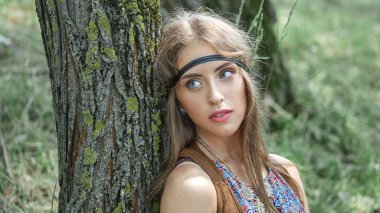 yakın çekim. ormandaki bir ağaç yakın duran güzel genç hippi kadın