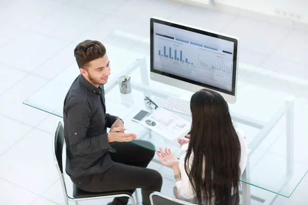 Twee medewerkers bespreken financiële gegevens zittend aan een bureau — Stockfoto