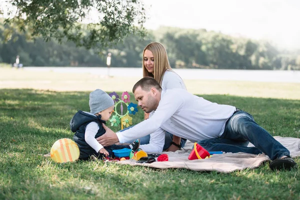 Šťastná rodina sedí na trávě v parku — Stock fotografie