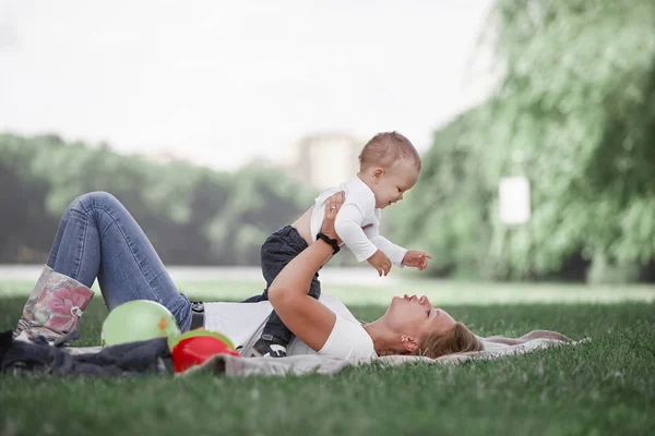 Mamá y su pequeño hijo juegan juntos, tumbados en el césped  . —  Fotos de Stock