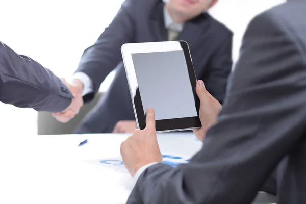 Empresário com um tablet digital no fundo de um aperto de mão de parceiros de negócios — Fotografia de Stock