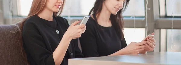 Werknemers met hun smartphones zitten aan een tafel in een café — Stockfoto