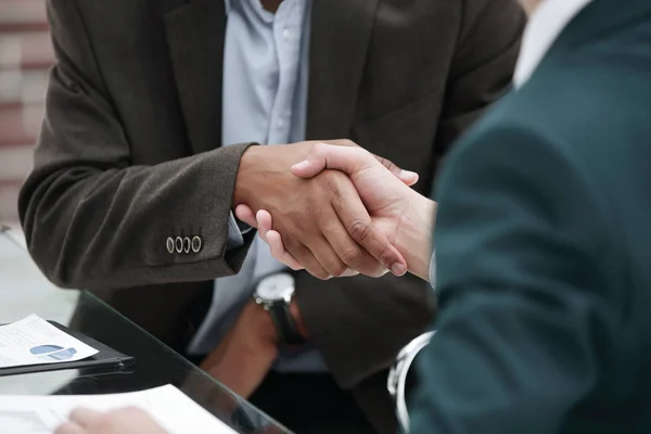 Handelspartner per Handschlag vor dem Hintergrund des Arbeitsplatzes — Stockfoto