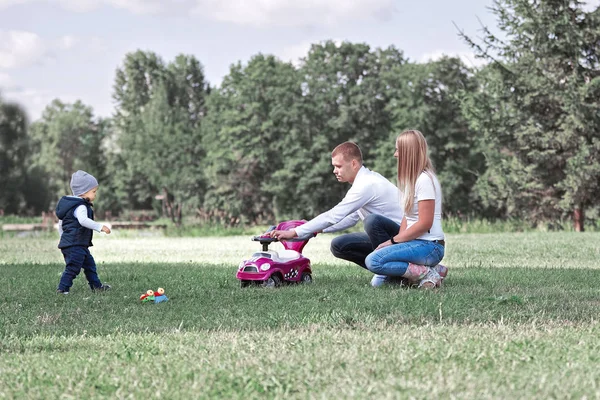 Батьки грають зі своїм маленьким сином на газоні в парку . — стокове фото