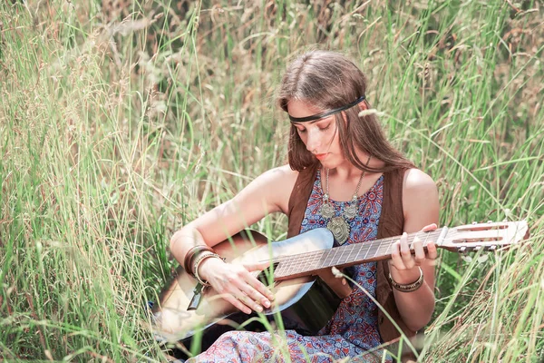 Mladí hippie žena hrající kytaru sedět na trávě — Stock fotografie