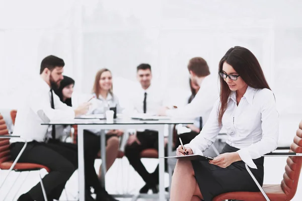 Mujer de negocios que firma un documento de negocios con su oficina borrosa fondo — Foto de Stock