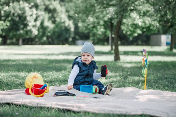 Grazioso bambino giocare con un giocattolo auto seduto sul prato — Foto Stock