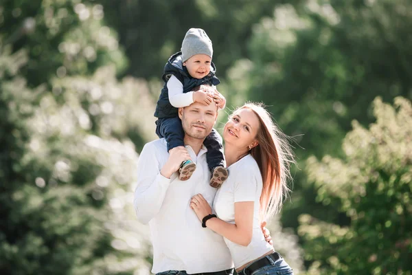 Glückliche Familie mit kleinem Sohn im Hintergrund eines Sommerparks. — Stockfoto