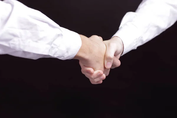 Close up. handshake business partners. isolated on black background — Stock Photo, Image