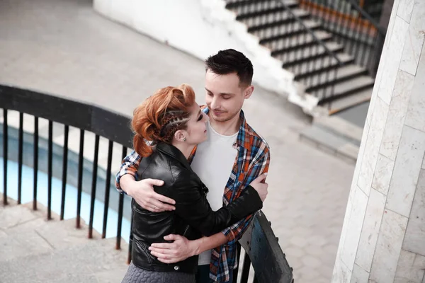 Mladý pár v lásce stojící v blízkosti zábradlí schodiště — Stock fotografie