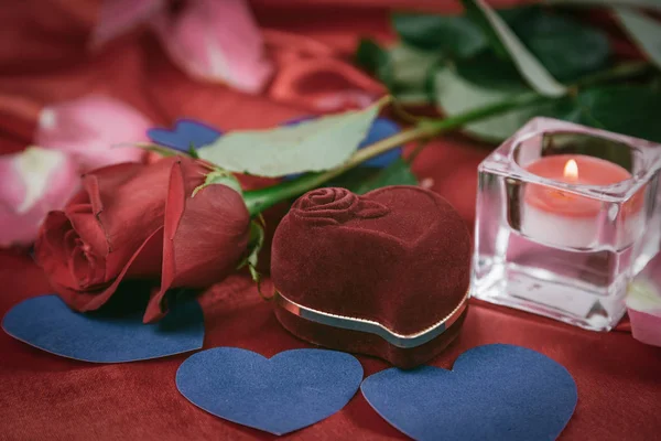 Dvě svíčky a růže na červeném hedvábí pozadí — Stock fotografie