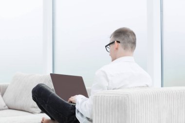 arka görüş.modern bir adam oturma odasında bir dizüstü bilgisayar üzerinde çalışıyor