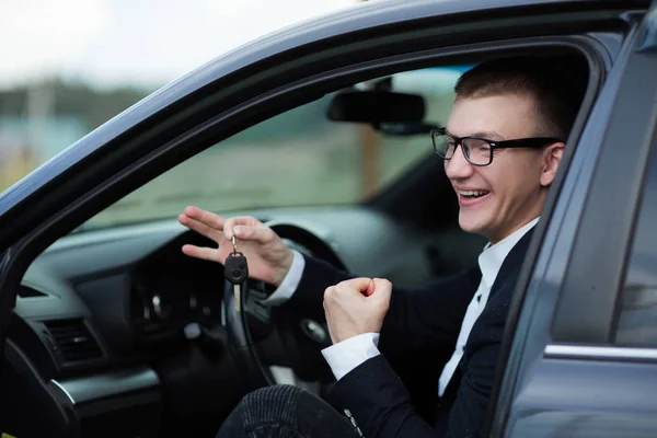 Szczęśliwy biznesmen siedzi w swoim nowym samochodzie i pokazując klucze — Zdjęcie stockowe