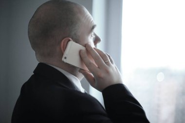 Ofis pencereden dışarı bakarak smartphone ile Dikiz .businessman.