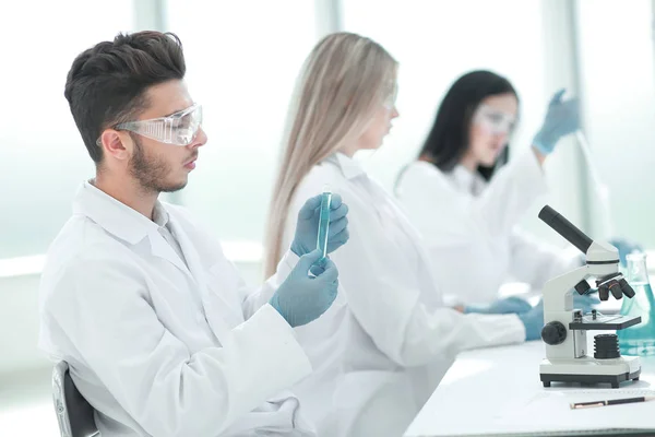 Grupo de jóvenes biólogos sentados en la mesa de laboratorio —  Fotos de Stock