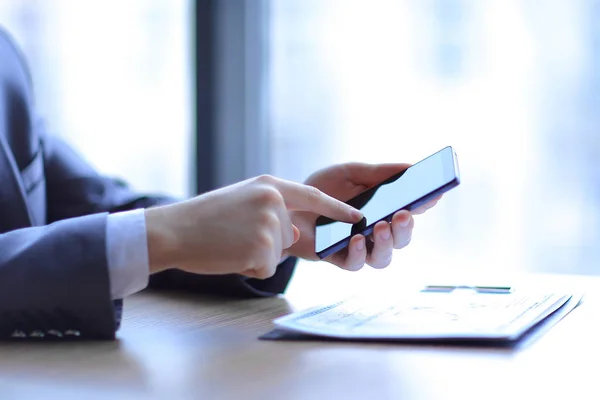 Nahaufnahme. Geschäftsmann tippt auf dem Smartphone, sitzt am Schreibtisch — Stockfoto