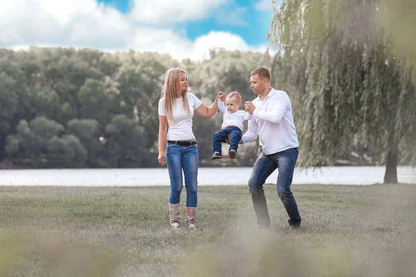 Счастливые родители со своим маленьким сыном, гуляющими вместе в весеннем парке — стоковое фото