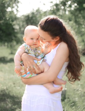 gülümseyen anne kucağında küçük kızı tutarak, konuşurken, sevgi ve hayranlık ile bebek bakarak