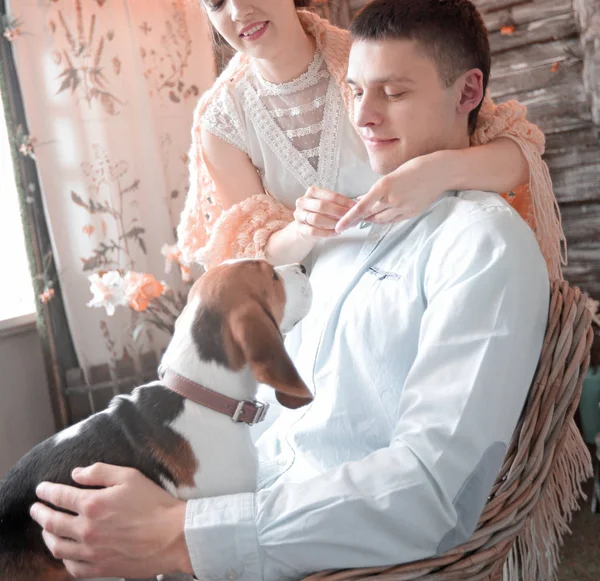 Молодая пара с домашним животным сидит на стуле — стоковое фото