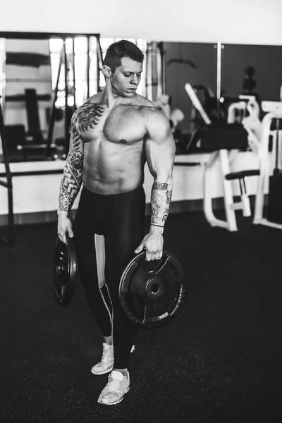 Σίγουρος νέος bodybuilder στέκεται σε ένα σύγχρονο γυμναστήριο. — Φωτογραφία Αρχείου