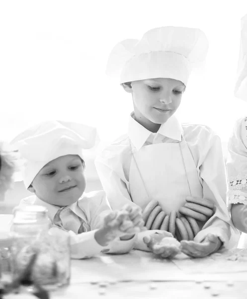 Three happy baby cooks standing near the kitchen table — Stock Photo, Image