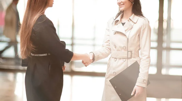 Dos mujeres de negocios estrechando la mano en el vestíbulo de la oficina . —  Fotos de Stock