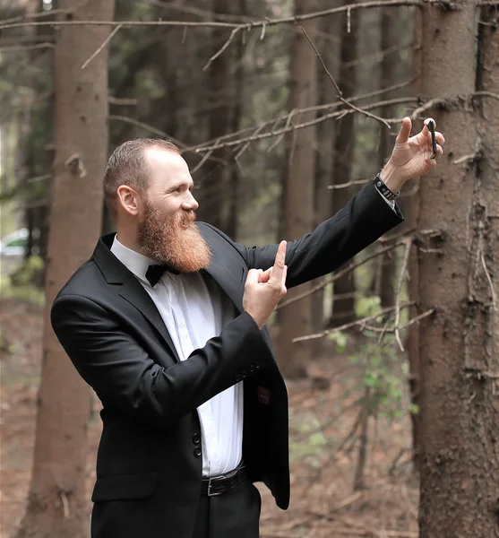 Успешный бизнесмен делает селфи в сосновом лесу — стоковое фото