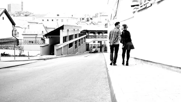 Priveliște din spate. Un cuplu îndrăgostit mergând pe trotuar într-un oraș modern . — Fotografie, imagine de stoc