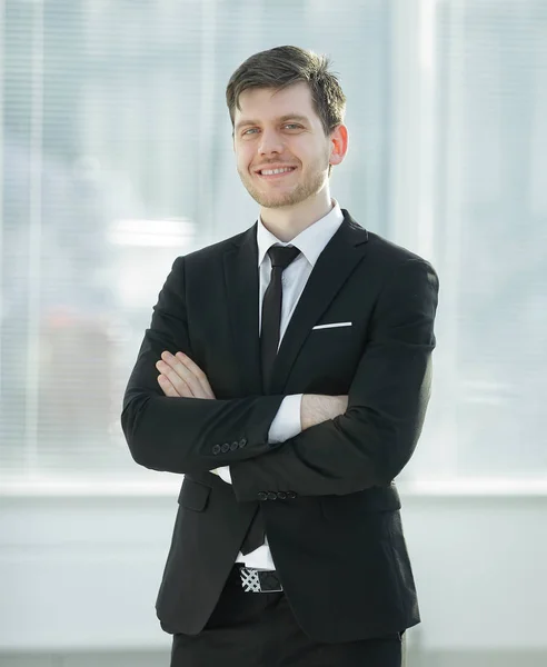 Jeune homme d'affaires souriant sur fond flou bureau — Photo