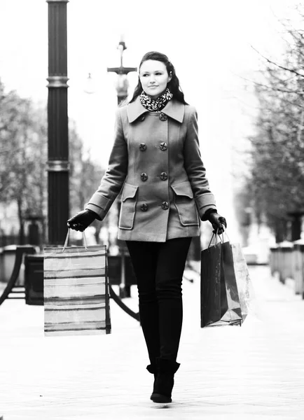 Ung kvinna med shoppingväskor går ner på gatan i ci — Stockfoto