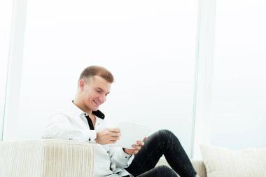 onun oturma odasında kanepede oturan dijital tablet ile gülümseyen adam