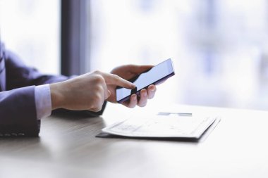 yakın kapatın. bir akıllı telefon üzerinde yazarak işadamı, Desk oturuyor