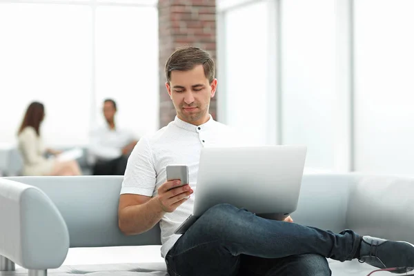 Modern man uses gadgets sitting in the lobby of a modern hotel — Stock Photo, Image