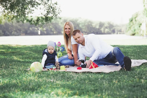 Glückliche Familie sitzt auf dem Gras im Park — Stockfoto