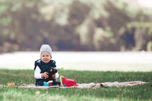Menino brincando com brinquedos sentados no gramado no parque — Fotografia de Stock