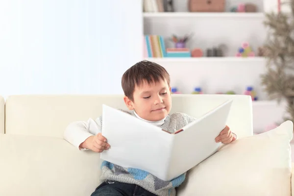 Bambino in età prescolare leggere un libro sul divano nella scuola materna — Foto Stock