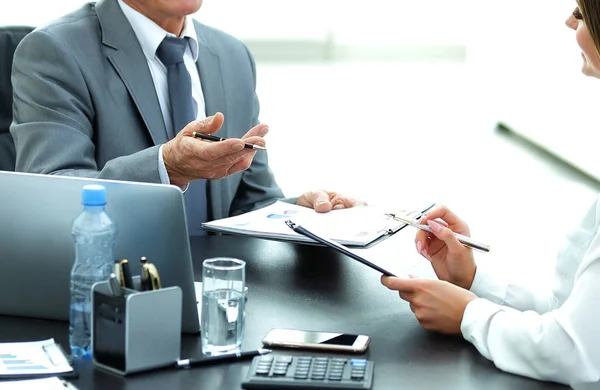 Empresário sênior conversando com seu jovem assistente na mesa — Fotografia de Stock