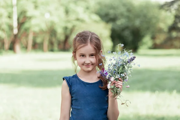 Маленькая девочка с букетом диких цветов. — стоковое фото