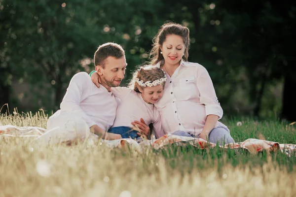 Happy family sitting on the grass on a summer day. — Stock Photo, Image
