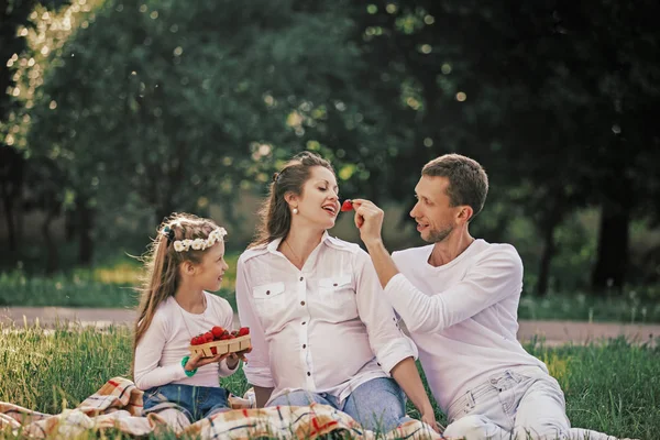 Família feliz desfrutando de morangos no piquenique — Fotografia de Stock