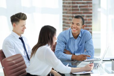 Çalışanlar masada oturan bir müşteriyle konuşuyor.