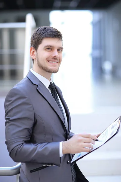 Empresário com o relatório financeiro sentado no lobby do escritório . — Fotografia de Stock