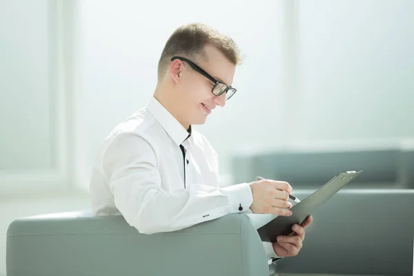 Homme d'affaires assis dans le hall du bureau et lisant un document d'affaires — Photo