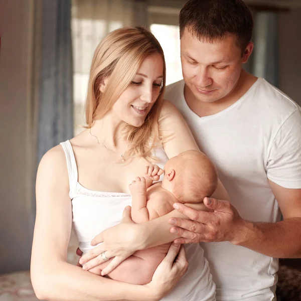 Happy family with newborn baby standing in their apartment — Stock Photo, Image