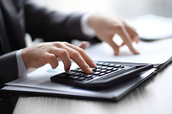 Z bliska. biznesmen sprawdza dane finansowe z kalkulatorem — Zdjęcie stockowe