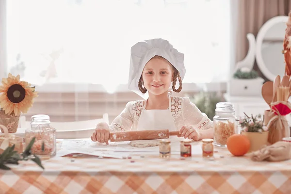 Очаровательная маленькая девочка в шляпе шеф-повара делает тесто для печенья — стоковое фото