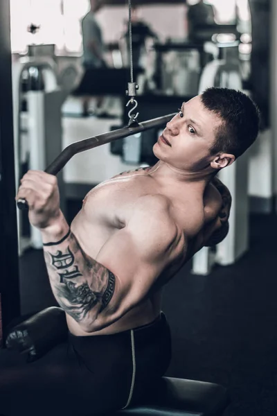 Αρσενικό bodybuilder χρησιμοποιεί τον προσομοιωτή για την ενίσχυση των μυών του θώρακα — Φωτογραφία Αρχείου