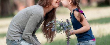 neşeli anne ve küçük kızı çim yaz gününde oturan